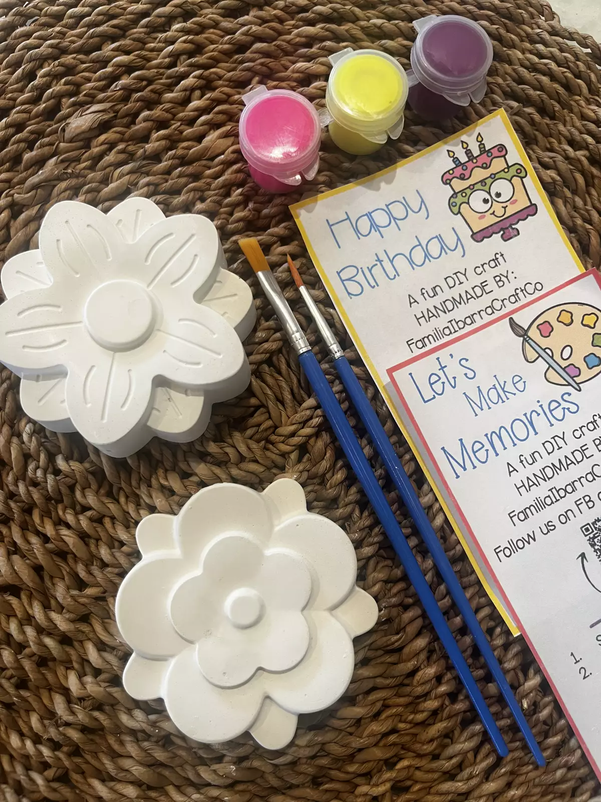 Three white plaster flowers with paint pots and two brushes