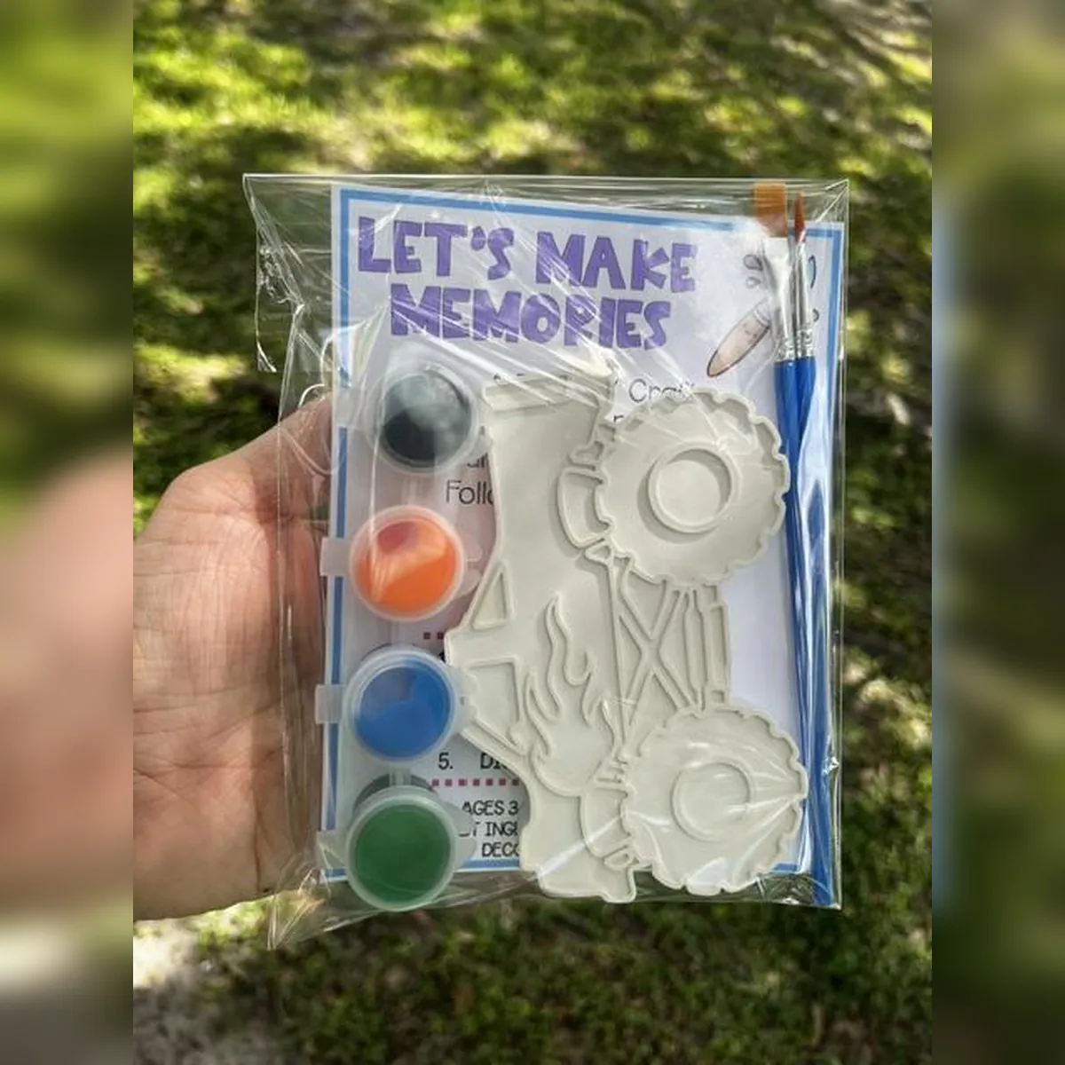 Packaged plaster monster truck kit with black, orange, blue, and green paint and a brush