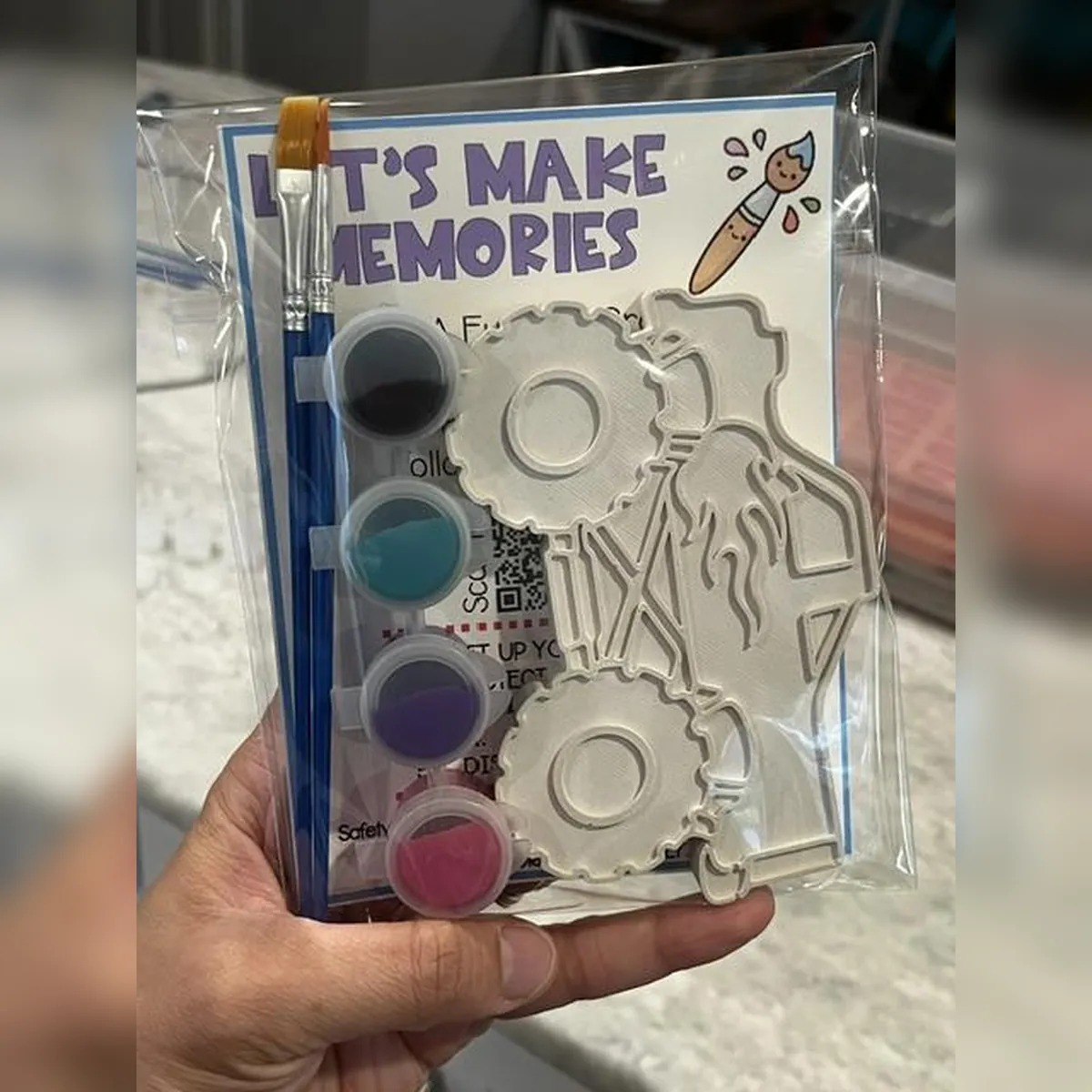 Packaged plaster monster truck kit with black, teal, purple, and pink paint and a brush