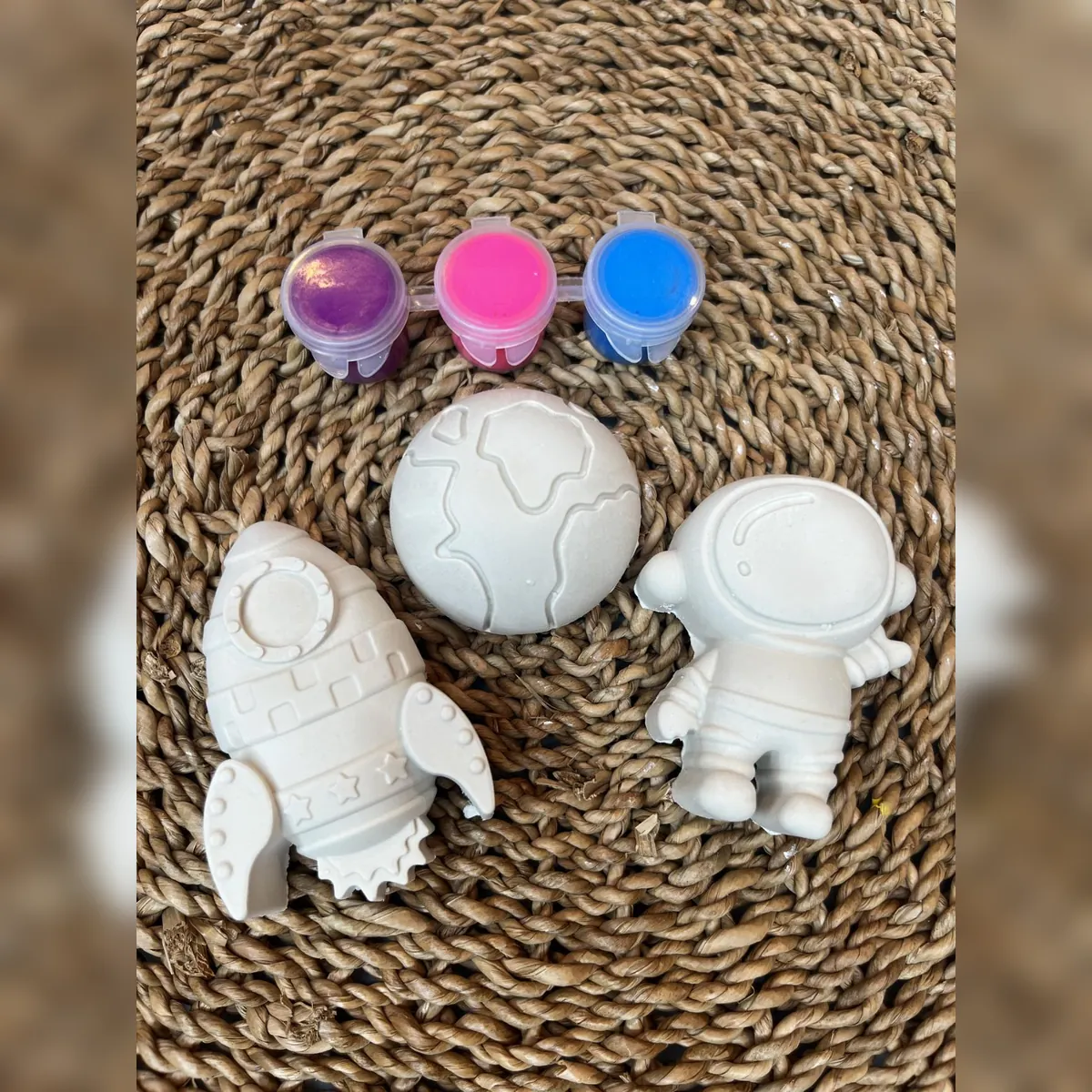 White plaster rocket, Earth, and astronaut with purple, pink, and blue paint