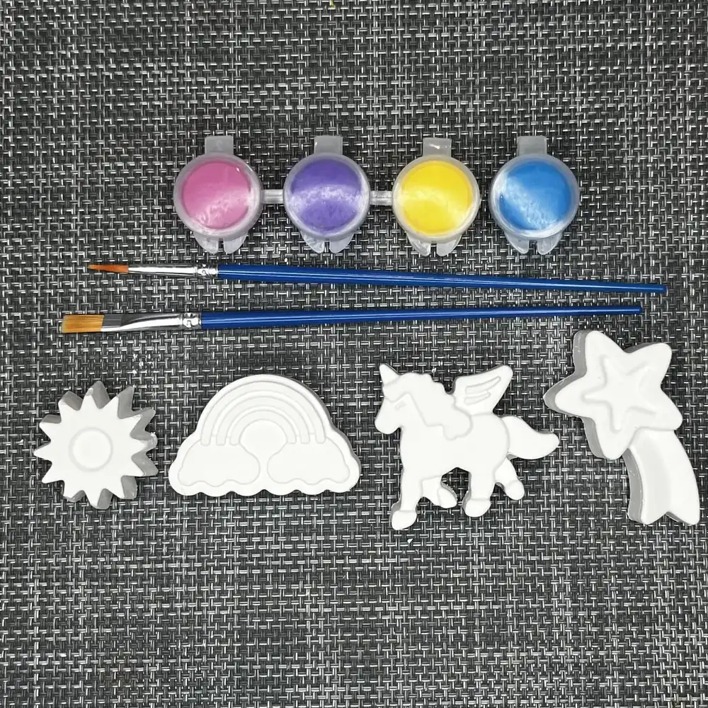 White plaster sun, rainbow, unicorn, and shooting star with pink, purple, yellow, and blue paint and two brushes